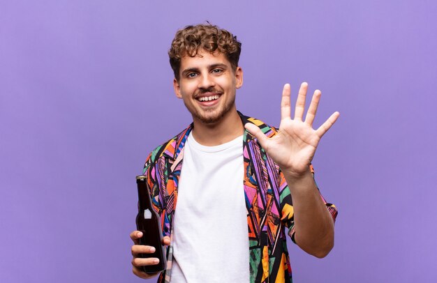 Joven sonriendo y mirando amigable, mostrando el número cinco o quinto con la mano hacia adelante, contando hacia atrás. concepto de vacaciones