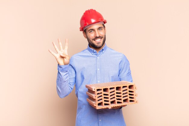 Joven sonriendo y mirando amigable, mostrando el número cuatro o cuarto con la mano hacia adelante, contando hacia atrás. concepto de arquitecto