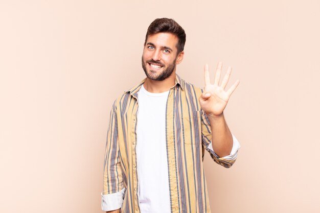 Joven sonriendo y mirando amigablemente, mostrando el número cuatro o cuarto con la mano hacia adelante, contando hacia atrás