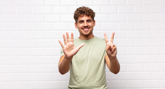 Joven sonriendo y mirando amigablemente, mostrando el número siete o séptimo con la mano hacia adelante, contando hacia atrás