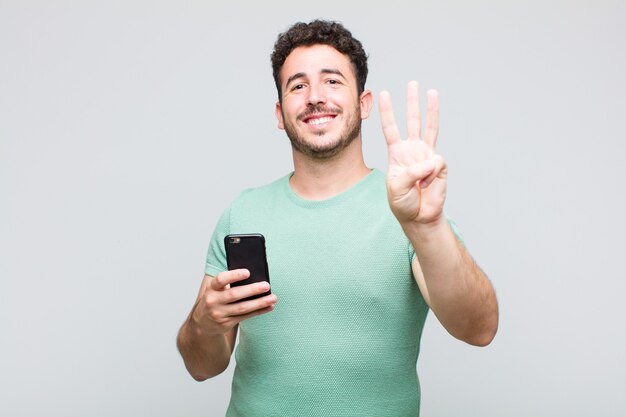 Joven sonriendo y mirando amistosamente, mostrando el número dos o el segundo con la mano hacia adelante, contando hacia atrás