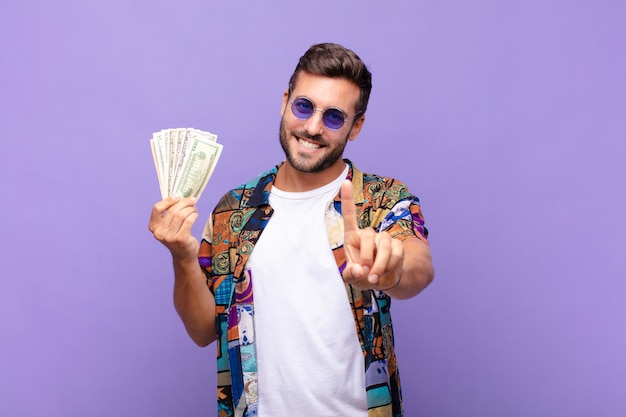 Joven sonriendo con orgullo y confianza haciendo la pose número uno triunfalmente, sintiéndose como un líder. concepto de vacaciones