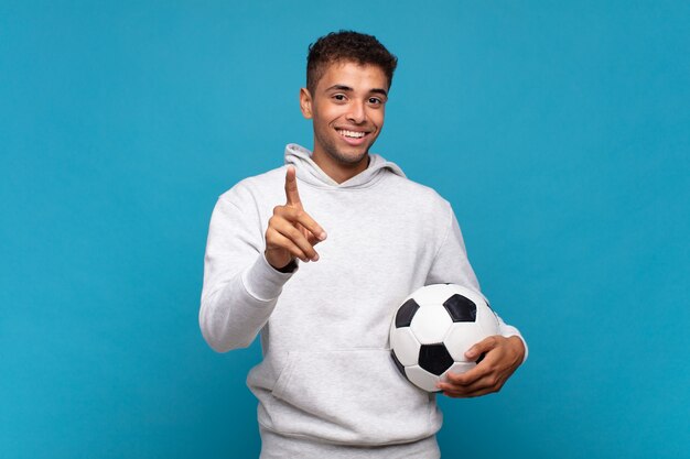 Joven sonriendo con orgullo y confianza haciendo la pose número uno triunfalmente