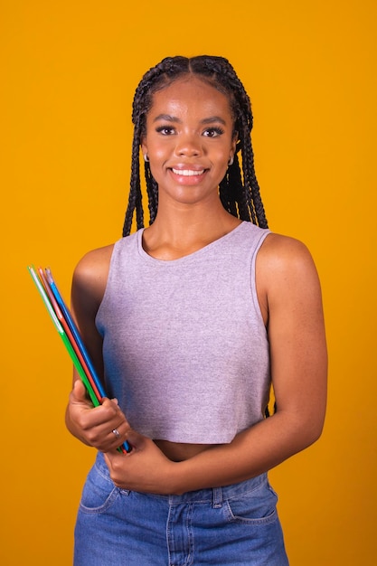 Foto joven sonriente afro niña feliz estudiante adolescente sosteniendo libros y cuadernos en el fondo con espacio libre para texto