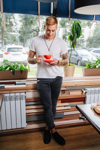 Joven sonriente apreciando su taza de café mirándola