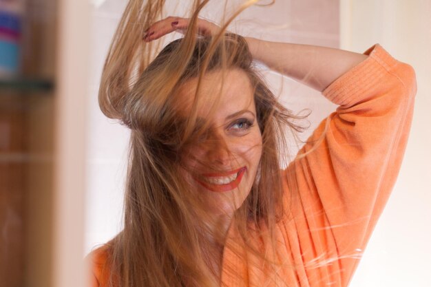 Una joven sonriente con el cabello desordenado en casa.