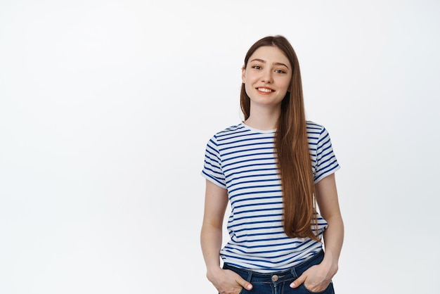 Joven sonriente en camiseta a rayas Adolescente feliz de pie relajado contra el fondo blanco.