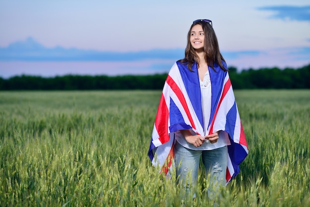 Joven sonriente en un campo de trigo. Bandera de la Gran Bretaña. El concepto de aprender inglés.