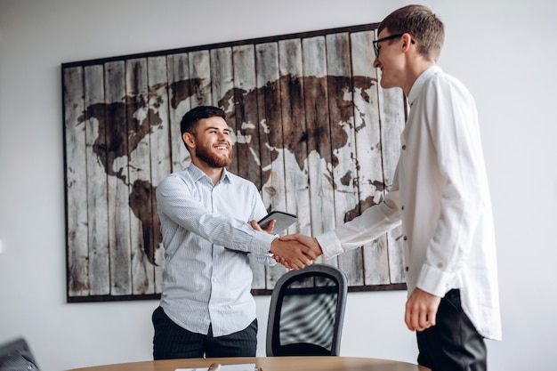 Foto joven sonriente dándole la mano a su socio comercial