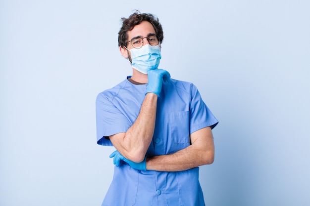 Joven sonriente, disfrutando de la vida, sintiéndose feliz, amable, satisfecho y despreocupado con la mano en la barbilla. concepto de coronavirus