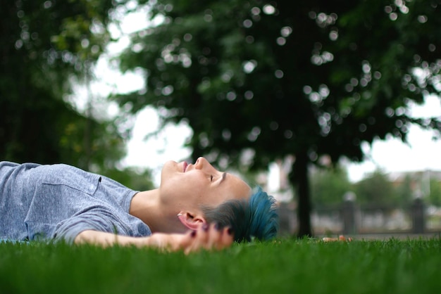 Una joven sonriente durmiendo en el campo de hierba.