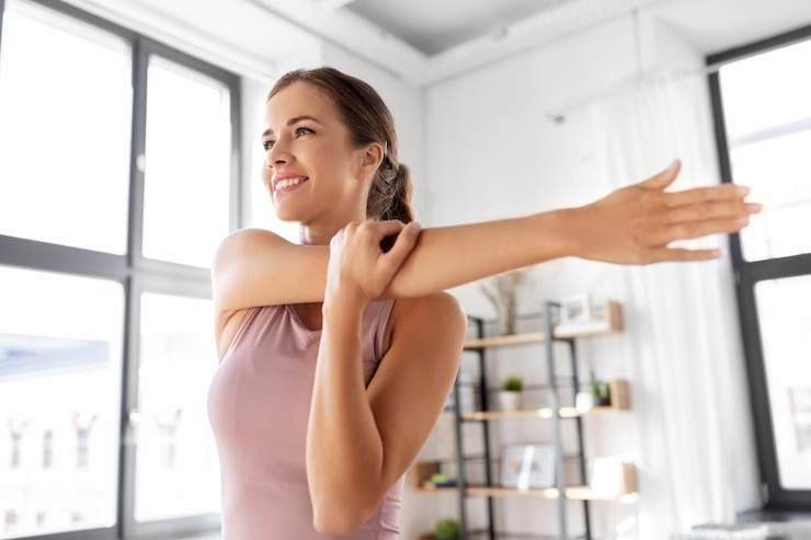 Foto una joven sonriente estirando el brazo en casa.