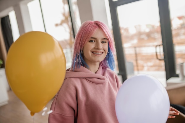 Una joven sonriente feliz con un montón de globos