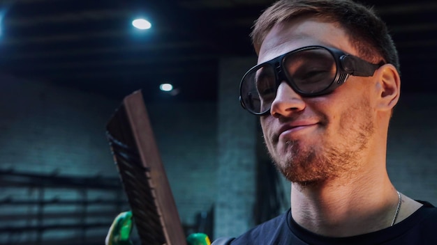 Joven sonriente con gafas mirando el detalle de metal que hizo