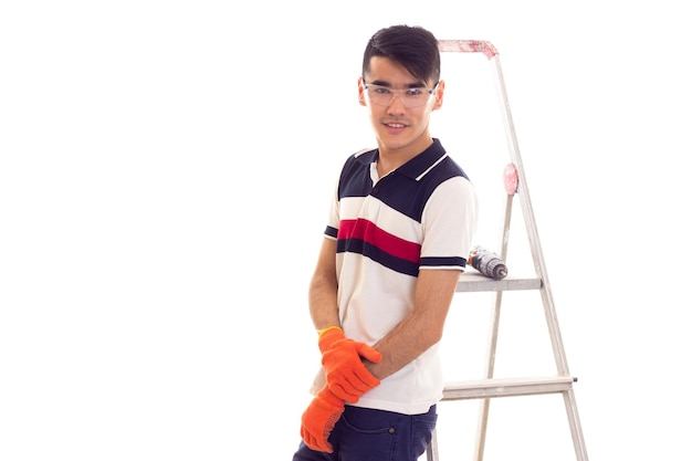 Joven sonriente con gafas protectoras de pie cerca del ledder con destornillador eléctrico