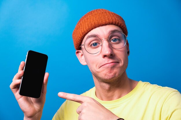 Foto un joven sonriente con gafas que muestra una aplicación de teléfono inteligente con pantalla limpia