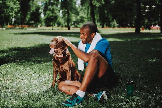 Joven sonriente hombre afroamericano acariciando perro.