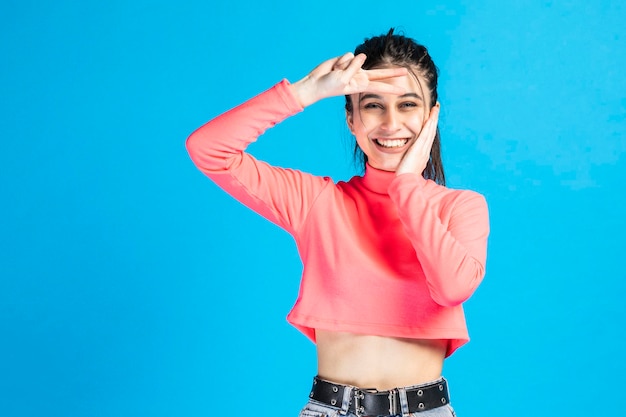 Una joven sonriente se lleva la mano a la cara y hace un gesto de paz