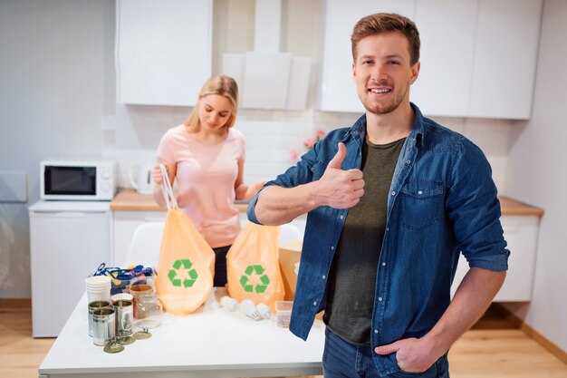 Joven sonriente mostrando el pulgar hacia arriba después de reciclar