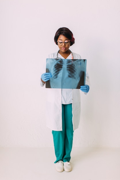 Joven sonriente mujer afroamericana médico en ropa médica con rayos x del paciente