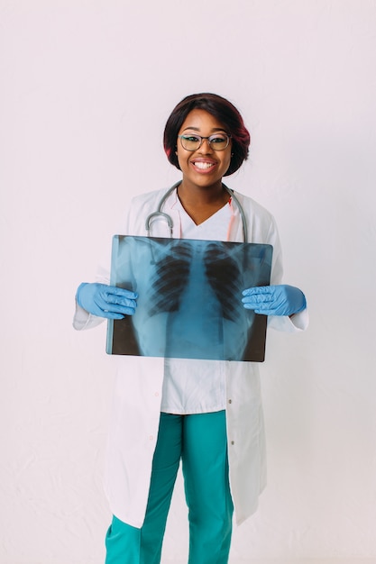 Joven sonriente mujer afroamericana médico en ropa médica con rayos x del paciente