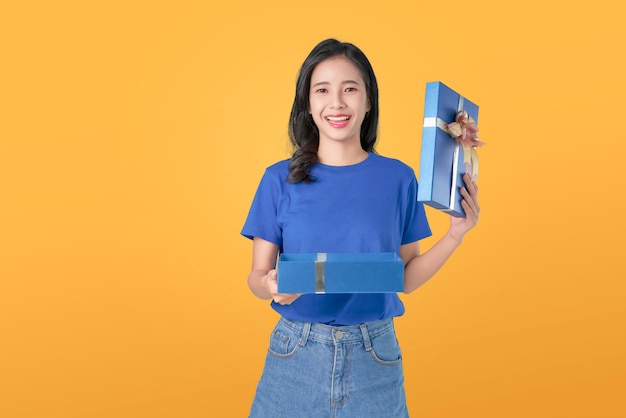 Joven sonriente mujer asiática en camiseta azul con regalo azul abierto