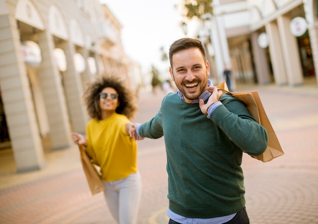 Joven sonriente pareja de compras en una calle urbana