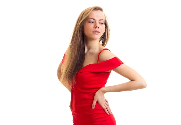 Una joven sonriente con el pelo largo y castaño con un vestido rojo diminuto de fondo blanco en el estudio