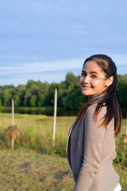 Una joven sonriente de pie en el campo contra el cielo