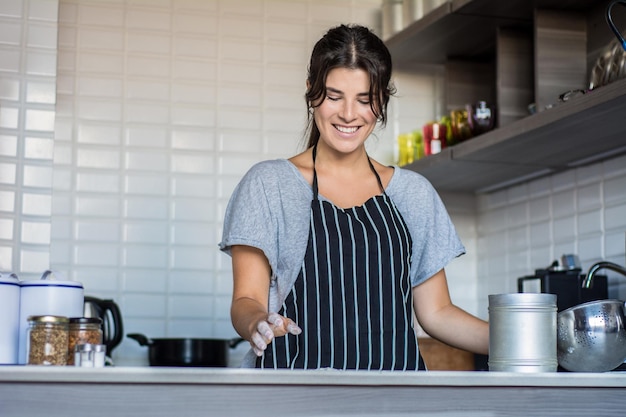 Foto una joven sonriente de pie en la cocina de su casa