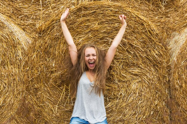 Una joven sonriente con una rubia con el pelo desaliñado en el fondo del heno