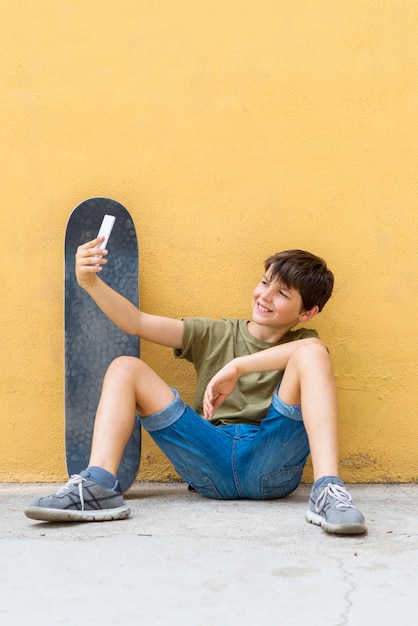 Foto una joven sonriente sentada contra la pared amarilla