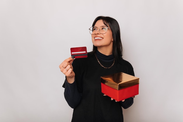 Una joven sonriente sostiene un regalo que recibió después de pagar con tarjeta de crédito