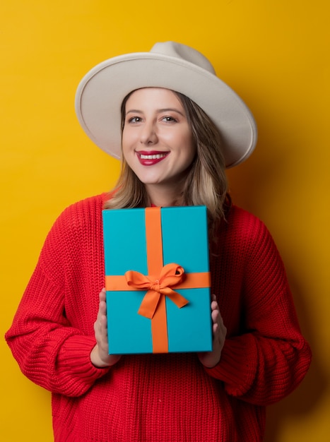 Joven sonriente en suéter rojo con caja de regalo