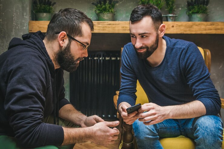 Foto un joven sonriente con el teléfono mirando a un amigo sentado en casa