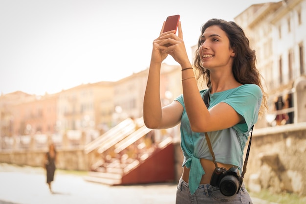 Foto una joven sonriente tomando una selfie en la ciudad.