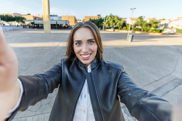 Foto joven sonriente tomando una selfie en la ciudad