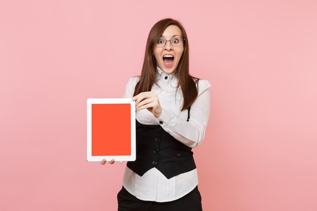 Joven sorprendida mujer de negocios con la boca abierta en vasos mantenga tablet pc con pantalla vacía en blanco aislada sobre fondo rosa. Jefa. Riqueza de carrera de logro. Copie el espacio para publicidad.