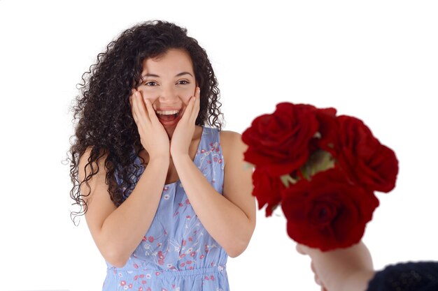 Joven sorprendida recibe ramo de rosas rojas.