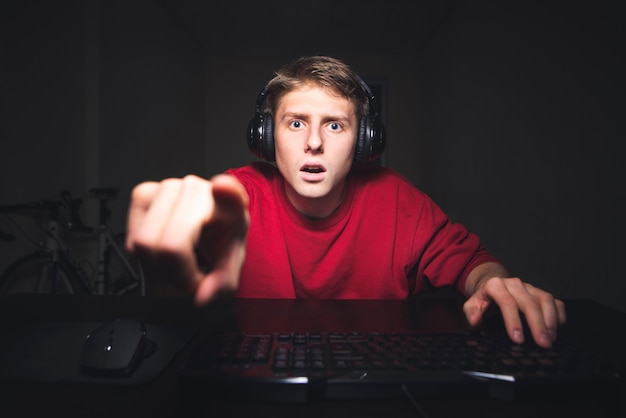 Joven sorprendido se sienta en los auriculares en su casa en la habitación