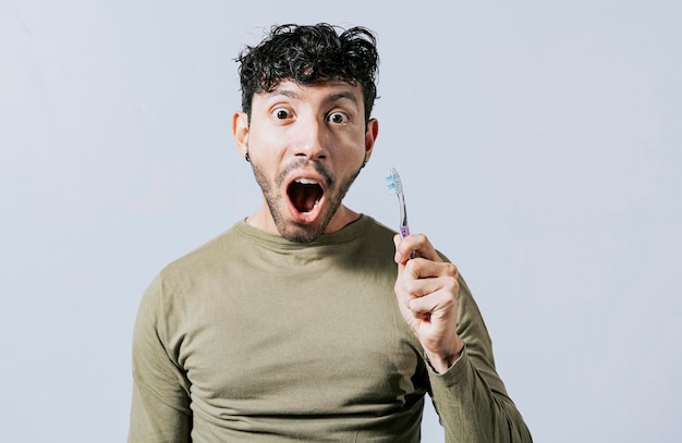 Joven sorprendido sosteniendo un cepillo de dientes Adolescente asombrado sosteniendo un cepillo de dientes aislado Chico sosteniendo un cepillo de dientes con cara asombrada aislado en blanco