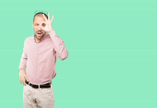 Joven sorprendido usando sus manos como un binocular