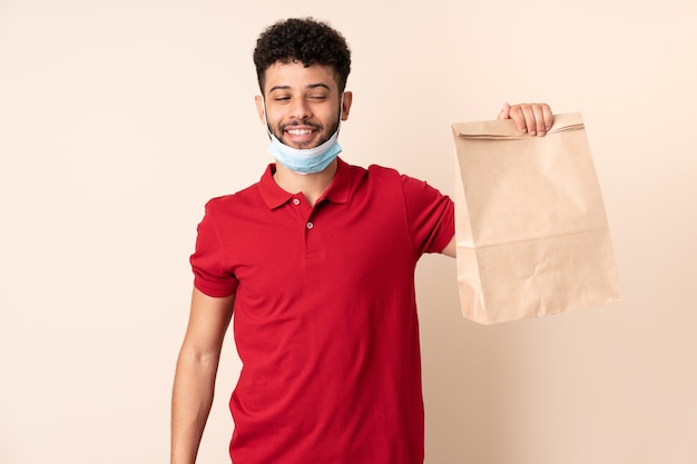 Joven sosteniendo una bolsa de comida para llevar ___ con expresión feliz