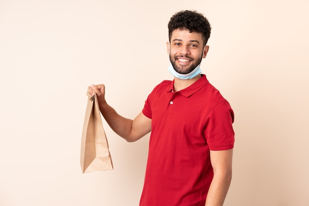 Joven sosteniendo una bolsa de comida para llevar ___ sonriendo mucho