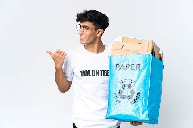 Joven sosteniendo una bolsa de reciclaje llena de papel apuntando hacia el lado para presentar un producto