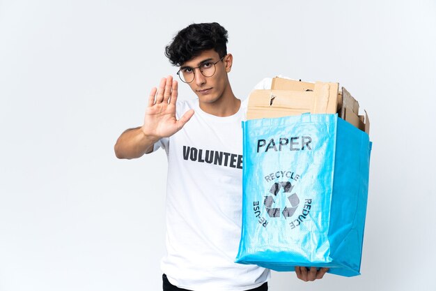 Joven sosteniendo una bolsa de reciclaje llena de papel haciendo gesto de parada