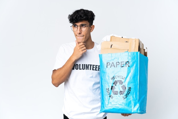 Joven sosteniendo una bolsa de reciclaje llena de papel teniendo dudas y pensando