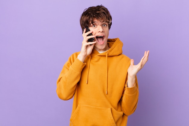 Joven sosteniendo una celda sintiéndose feliz y asombrado por algo increíble