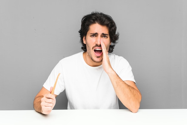 Joven sosteniendo un cepillo de dientes gritando emocionado al frente.