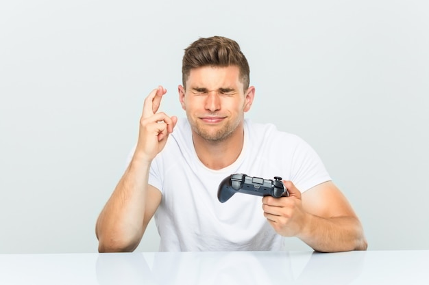 Joven sosteniendo un controlador de juego cruzando los dedos para tener suerte